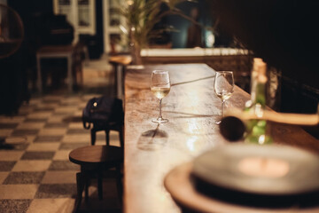 Obraz premium Two glasses of white wine in a dark cozy bar. Wine served on a wooden table
