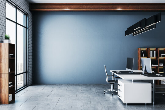 Coworking office in a loft style interior with blank blue wall.