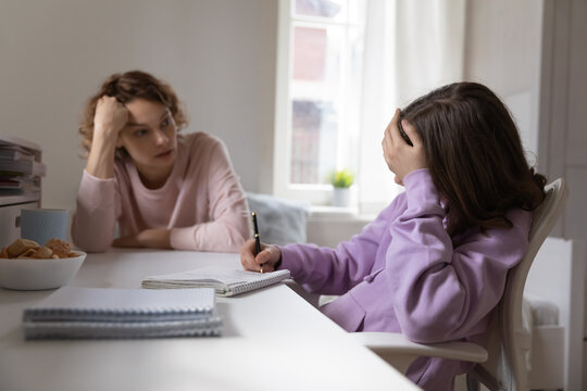 Caucasian Mom Help Distressed Unhappy Teenage Daughter With Homework Preparation, Have Problems With Distant Education. Stressed Teen Girl Child Feel Unmotivated Bored Studying At Home With Mother.