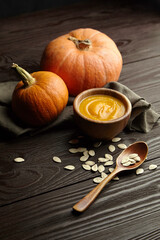 Pumpkin cream soup in bowl on wooden background