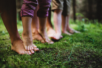 Bare feet of family with small children standing barefoot outdoors in nature, grounding concept.