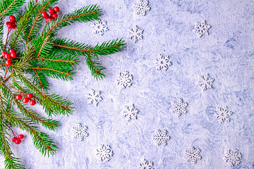 Christmas background with green Christmas tree branches, decorated with red berries and wooden snowflakes. Christmas card with space for text. Winter break time.