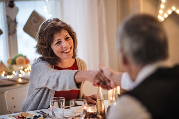 Happy senior couple in love indoors at home sitting at the table at Christmas, talking.