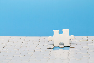 Unfinished white jigsaw puzzle on blue background with copy space. Business strategy teamwork and...