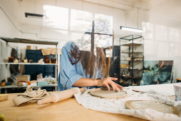 young woman, potter, makes utensils with their own hands in their own workshop