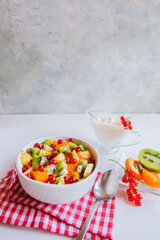 Bowl of healthy fresh fruit salad on white table. The view from the top. Healthy vegan lunch.