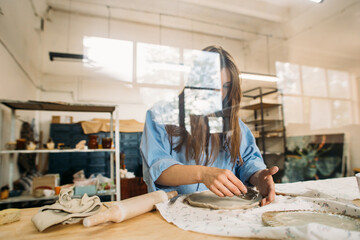 young woman, potter, makes utensils with their own hands in their own workshop