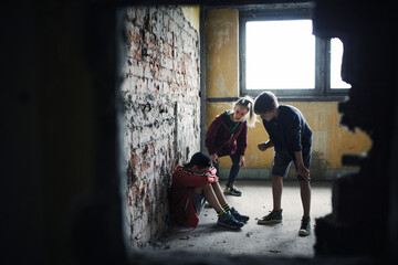 Teenage boy attacked by thugs in abandoned building, gang violence and bullying concept. - obrazy, fototapety, plakaty