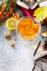 Healthy autumn vitamin drink. Hot Sea buckthorn tea with lemon with fresh sea buckthorn berries on a stone countertop. Copy space.