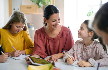 Group of homeschooling children with teacher studying indoors, coronavirus concept.