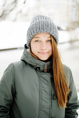 Charismatic smiling young woman with natural make-up in winter warm outfit posing outdoors in snowy park