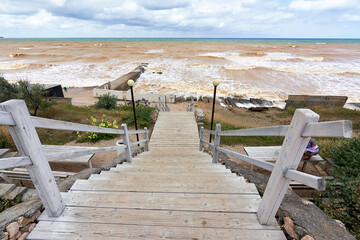 Old wooden staircase with railings descending to the sea beach