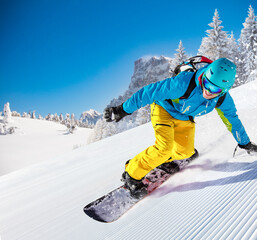 Snowboarer going downhill during sunny day in high mountains