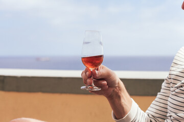 Tasting of Madeira wine in man's hands, ocean on the background