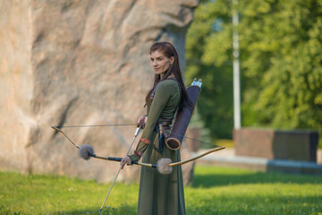 A stately woman in a suit of an arrow on the background of a large stone