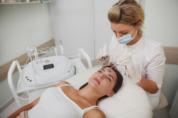 Woman getting professional facial cosmtology treatment by cosmetologist
