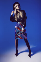 Blonde stylish woman in black hat and multi skirt