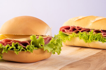 Mortadella, cheese and lettuce sandwiches on wooden surface, gray background, selective focus.