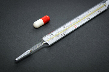 Set for flu treatment capsules and thermometer. Means of protection against viruses and epidemics on a dark background