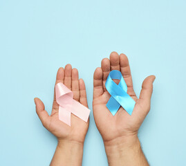 female hand holding pink ribbon bow, male hand holding blue ribbon