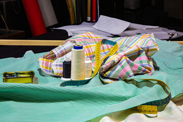 Detalle de mesa de costura con telas, metro e hilo de coser