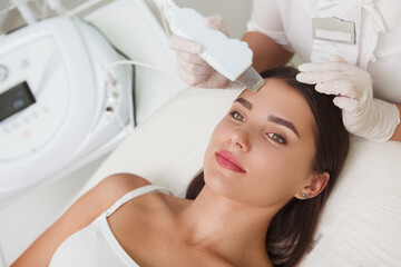 Top view close up of a cheerful young woman smiling while getting professional ultrasound cleanse at beauty salon