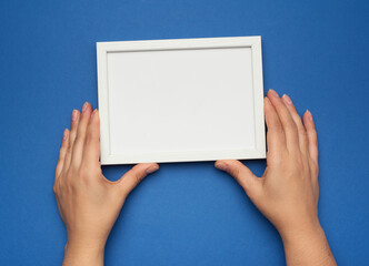 two female hands holding a rectangular blank white frame