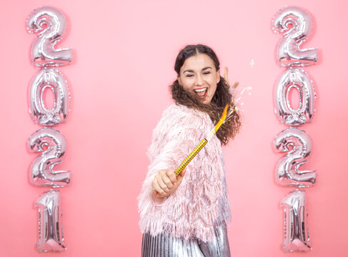 Young Woman On A Pink Background With Silver Ballons In The Form Of The Numbers 2021