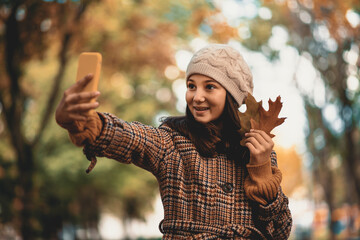 Teenage girl taking selfie in the park on autumn day