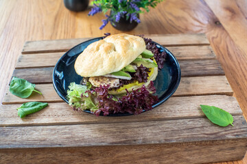 Grilled chicken and avocado sandwich on wooden table background