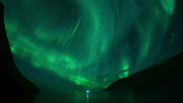 Full sky aurora borealis over ships in steep ford nothern Iceland