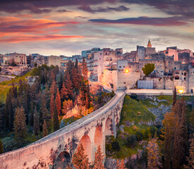 Old viaduct over a deep canyon. Colorful spring sunrise on Gravina in Puglia town. Stunning morning...