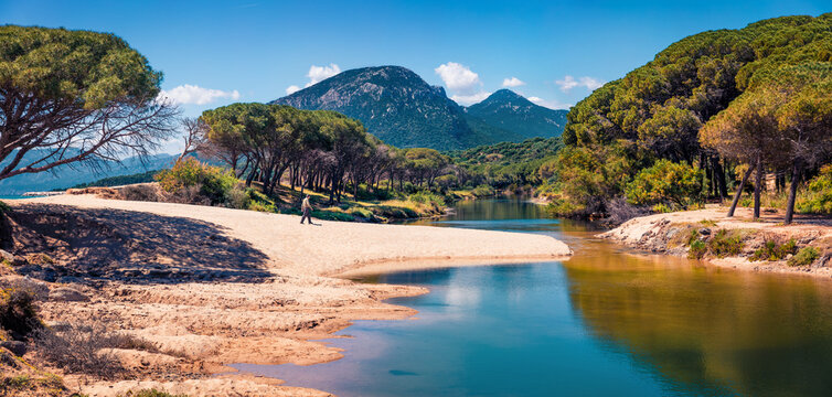 Tourist walking on the shore of  Osala Beach. Bright spring scene of Sardinia island, Italy, Europe. Beautiful seascape of Mediterranean sea. Traveling concept background.