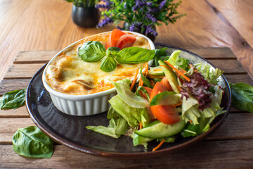 Traditional Italian lasagna with fresh salad vegetables, On a wooden try