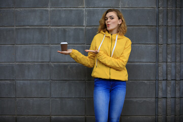 Woman in yellow jacket demonstrate a takeaway coffee
