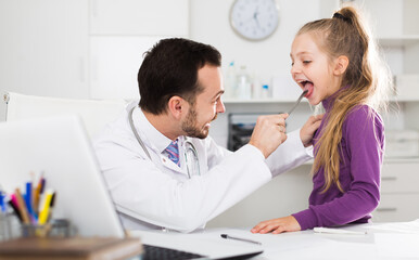 Fototapeta premium Little smiling girl visiting consultation with man doctor in hospital