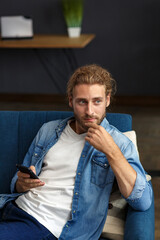 Fototapeta premium Curvy guy using smartphone and smiling. Happy man using mobile phone apps, texting message, browsing internet, looking at smartphone, sitting at home. Young people working with mobile devices.