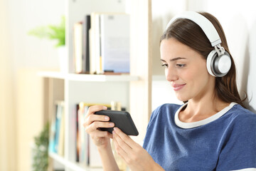 Smiley teen watching media on smart phone wearing headset