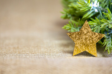 Fototapeta na wymiar close-up of a gold glossy star with green wreath and white lights, shiny christmas decoration with green leaves on jute, background, front view