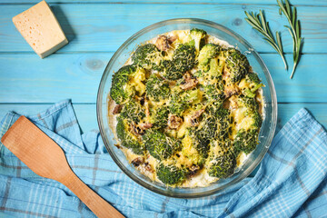 Broccoli cheddar egg casserole in baking dish on blue wooden background.