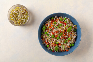 Trendy lunch with rice and vegetables. Served in a blue bowl, on a bright painted background. Top view.