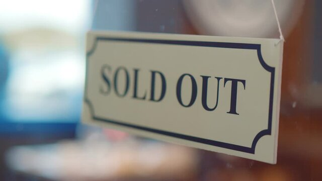 Close up of human hand hanging sold out sign on glass door of cafe or store
