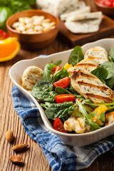 Traditional Greek salad with grilled Halloumi cheese with basil. Front view.