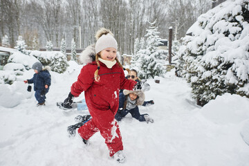 Fototapeta na wymiar A cute children playing in snow outdoor near the christmas trees
