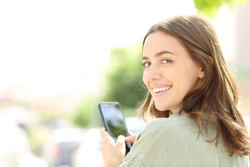 Happy woman using phone smiling at camera