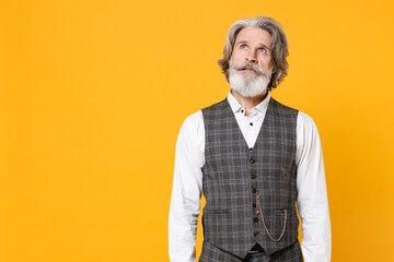 Pensive elderly gray-haired mustache bearded business man in checkered suit waistcoat white shirt standing looking up isolated on yellow background studio portrait. Achievement career wealth concept.
