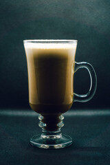 Creamy Irish coffee in a glass on black background. Shallow depth of field, blur, whiskey, drink, bokeh, Christmas.