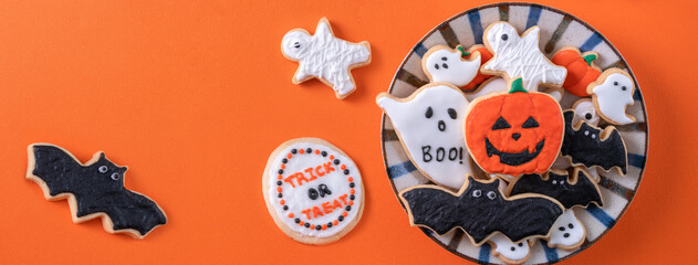 Top view of Halloween festive decorated icing sugar cookies on orange background.