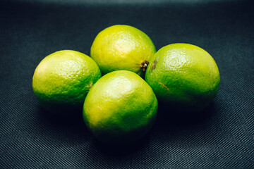 Four green limes on black background. Shallow depth of focus, blur, fruit, 4.