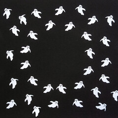 Halloween background. White confetti ghosts on black paper background. Happy Halloween concept. Greeting card, festive backdrop for Halloween holiday. Flat lay, top view, copy space